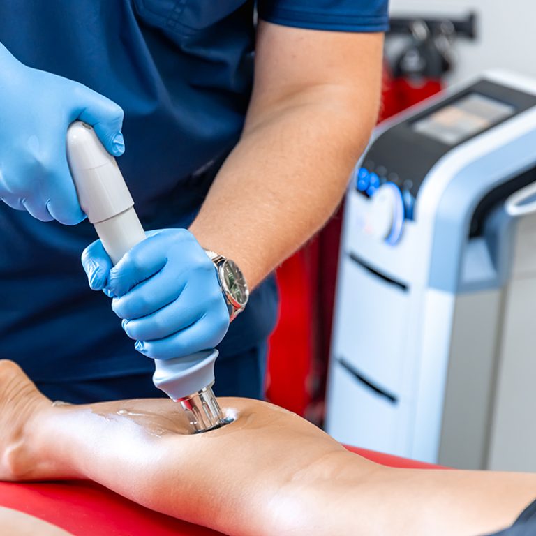 Shock wave therapy, the magnetic field, rehabilitation, physiotherapist doctor performs surgery on a patient's shin.